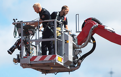 Foto på två brandmän uppe i korgen på ett höjdfordon.