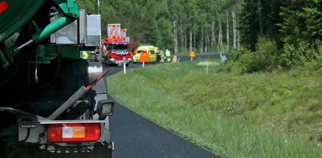 Foto på bilkö bakom en trafikolycka med räddningstjänst och ambulans på plats