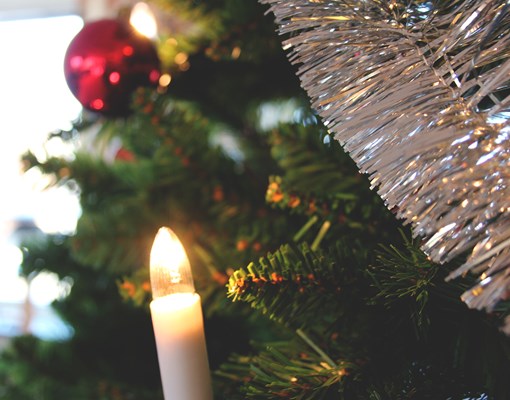 Närbild på julgranskula och julgransljus i en julgran.